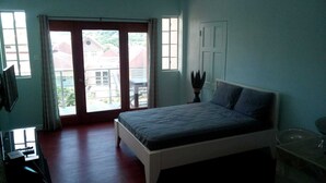 Un dormitorio con cama, escritorio, silla, ventana y puerta.