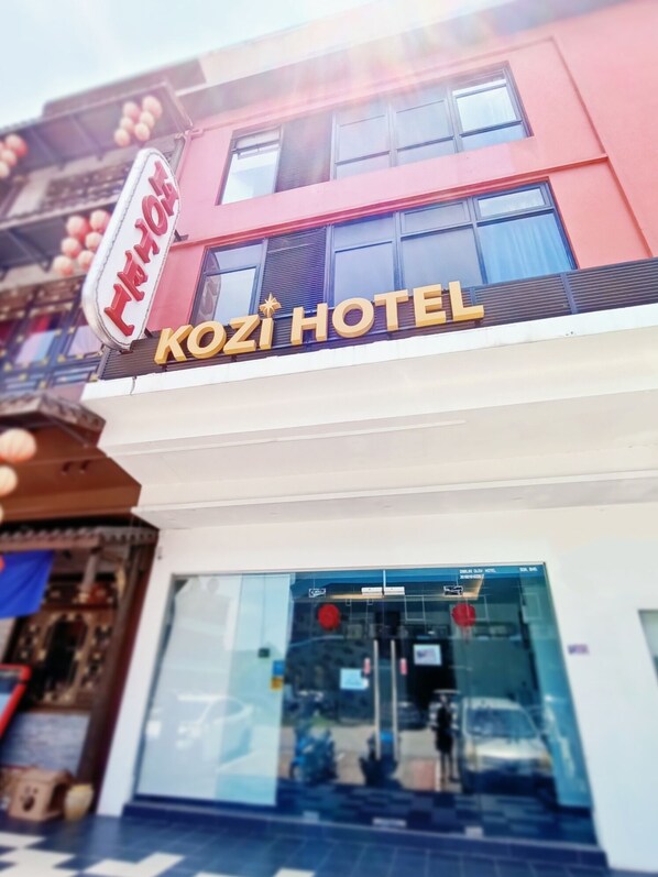 Un letrero de hotel con la inscripción 'KOZI HOTEL' en letras doradas sobre fondo blanco.