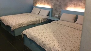 Une chambre d’hôtel avec deux lits, chacun recouvert d’une couvre-lit à motifs et agrémenté d’oreillers assortis. La chambre est dotée d’un mur à texture et d’une petite table de chevet avec une lampe.