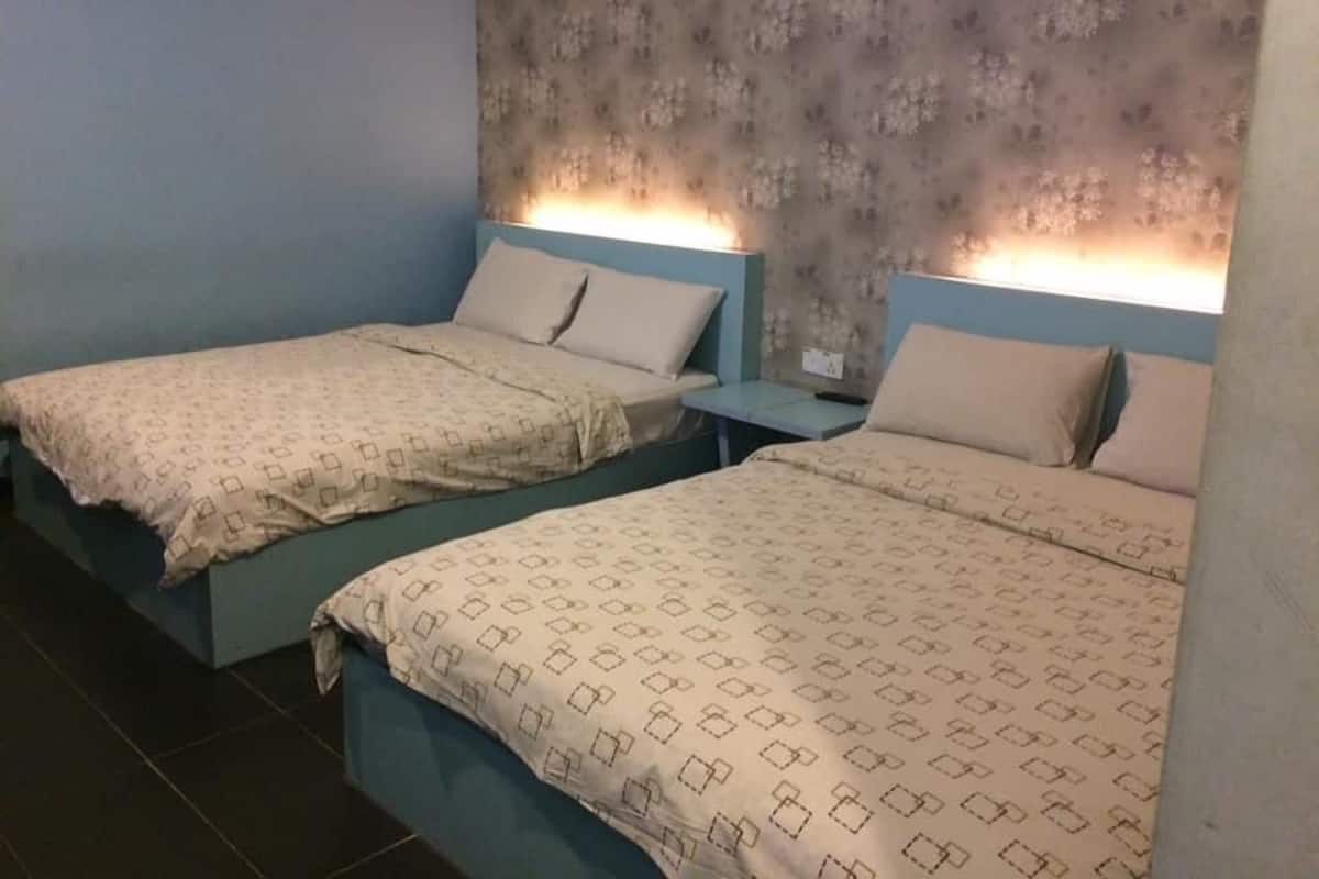 Une chambre d’hôtel avec deux lits, chacun recouvert d’une couvre-lit à motifs et agrémenté d’oreillers assortis. La chambre est dotée d’un mur à texture et d’une petite table de chevet avec une lampe.