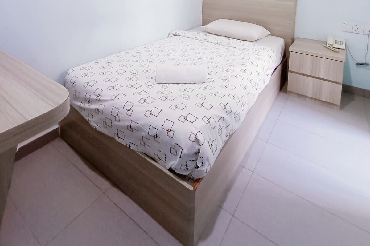Une chambre bien rangée, avec un lit, une table de chevet et un petit bureau.