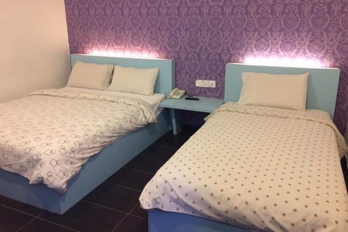Deux lits simples avec des têtes de lit, une table de chevet avec un téléphone et un mur décoré d’un motif.