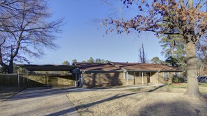 A two-story residential building with a covered garage and a large tree in front. - A Quiet Place - Dogwood Retreat in Texarkana (Texarkana)