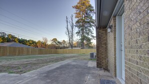 A backyard with a concrete patio, a wooden fence, and a brick wall. - A Quiet Place - Dogwood Retreat in Texarkana (Texarkana)