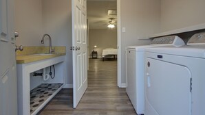 A laundry room with a washing machine, a sink, and a door leading to a bedroom. - A Quiet Place - Dogwood Retreat in Texarkana (Texarkana)