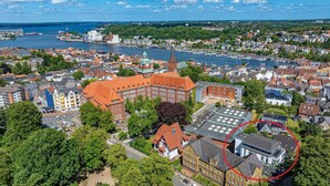 An aerial view of a city with a prominent church, a marina, and residential buildings.