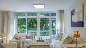 A modern living room with a large window, white furniture, and a minimalist decor.