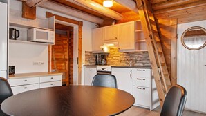 A cozy kitchen with wooden beams, a round table, and modern appliances. - Rustholli 9 by Interhome (Tampere)