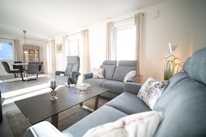 Una sala de estar moderna con un sofá gris, una mesa de centro y una zona de comedor con una mesa y sillas.