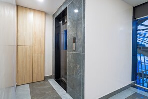 A modern elevator with a digital display, a wooden door, and a marble wall. - Treebo The Address Inn Mehdipatnam (Hyderabad)