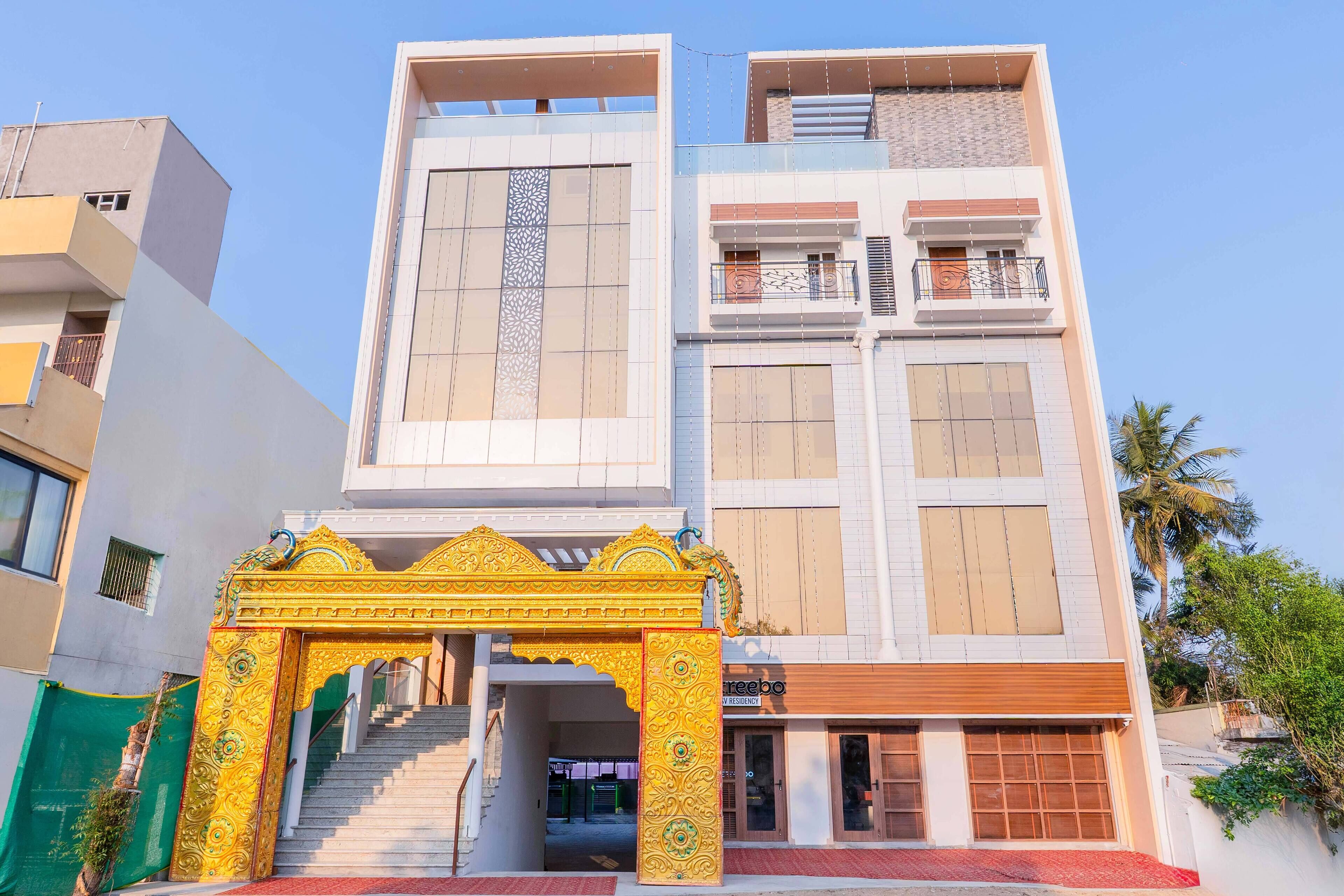 Un edificio de varios pisos con una escalera central, una entrada decorativa y un espacio comercial en la planta baja.