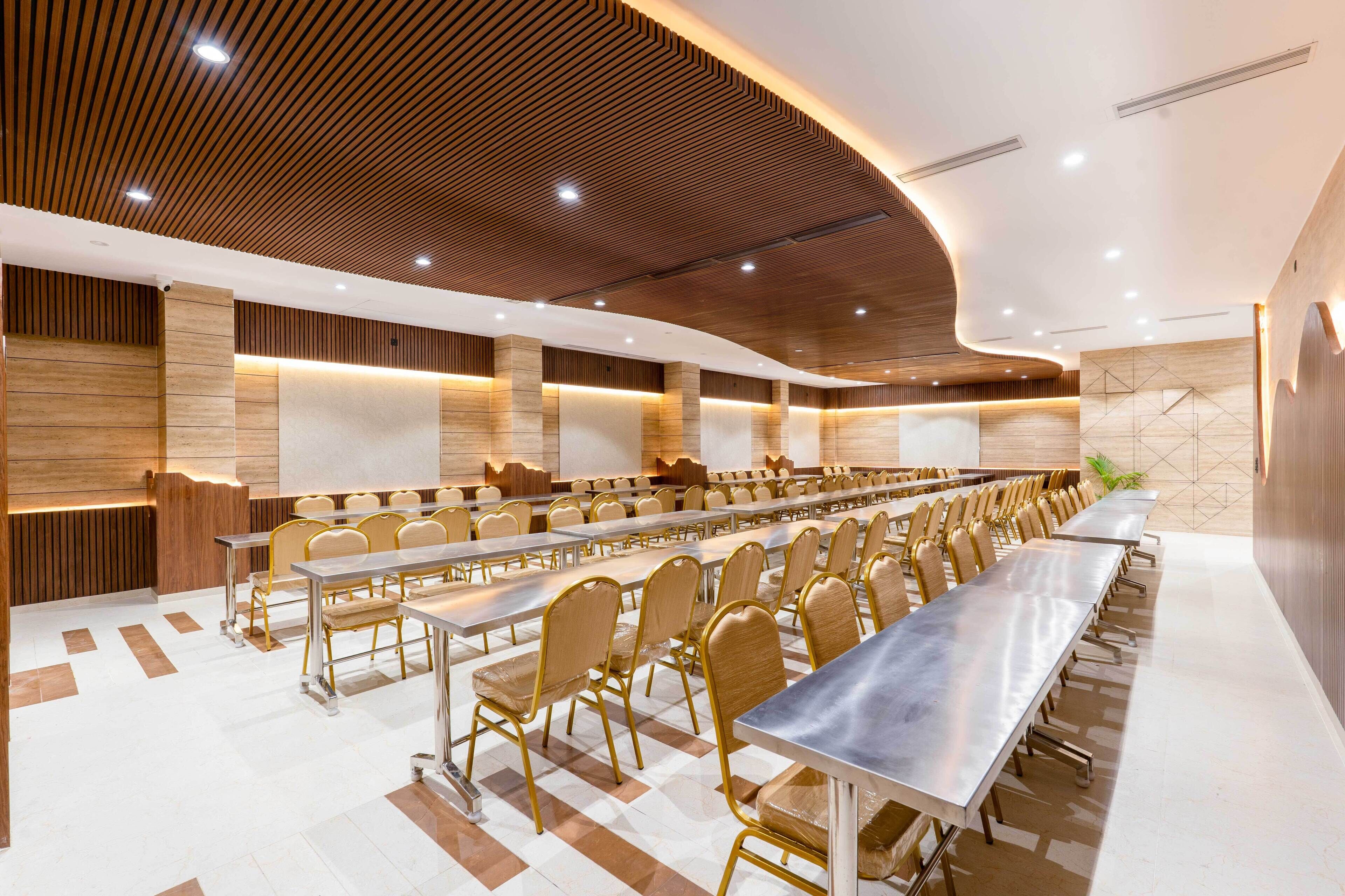 A conference room with long tables and chairs, wooden paneling on the walls, and recessed lighting.