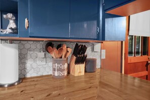 A kitchen with blue cabinets, a wooden countertop, and a utensil holder.