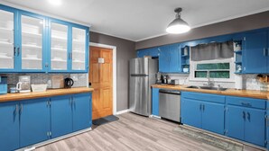 A modern kitchen with blue cabinets, stainless steel appliances, and a wooden countertop. - Madolyn Executive Retreat 30 + Day Stays Welcomed - 4 Beds - Covered Patio (Montgomery)