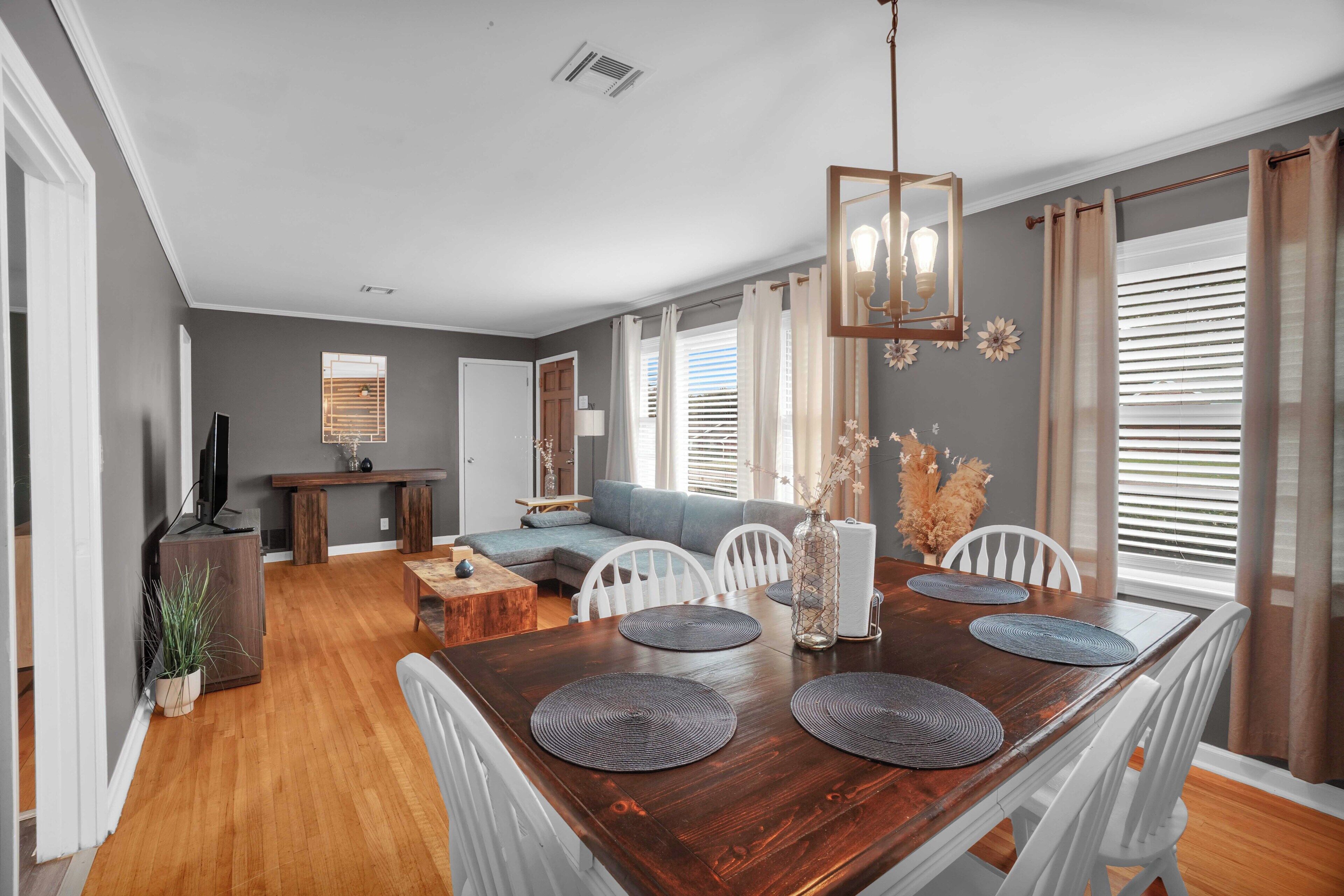 A dining area with a wooden table, white chairs, and a chandelier.