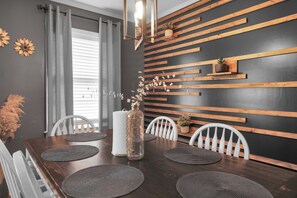 A dining area with a dark wooden table, white chairs, and a wall with horizontal wooden slats.