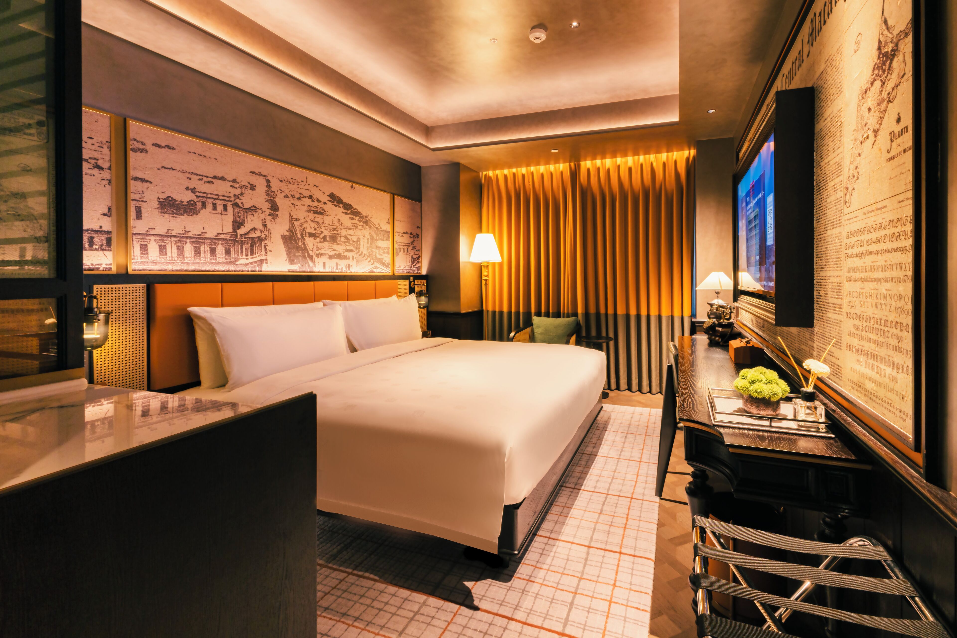 Una habitación de hotel con una cama grande, un escritorio con lámpara y un televisor.