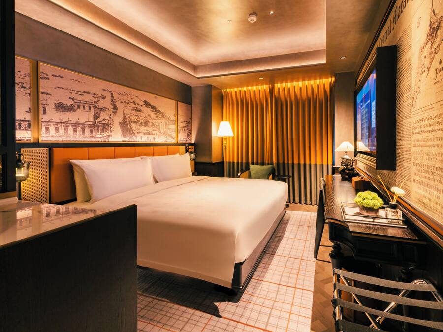 Una habitación de hotel con una cama grande, un escritorio con lámpara y un televisor.