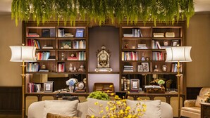 A cozy living room with a sofa, a bookshelf filled with books and decorative items, and a large clock. - Hotel Central (Macau)