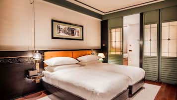 A neatly arranged bedroom with a large bed, a bedside table with a lamp, and a framed picture on the wall.