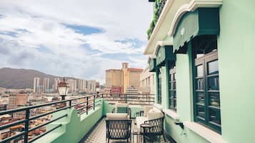 Un balcón con vistas a un paisaje urbano, incluyendo edificios altos y una montaña al fondo.