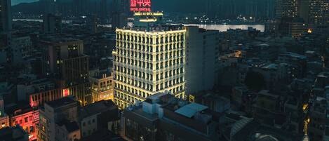 A high-rise hotel with multiple floors and balconies, surrounded by a dense urban area with other buildings.