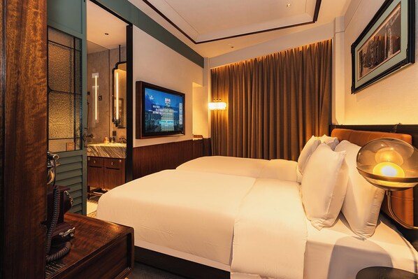 A hotel room with a large bed, a television, a desk with a telephone, and a mirror. - Hotel Central (Macau)