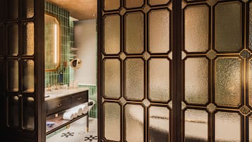 A bathroom with a dark wooden door, a white sink, and green tiles.