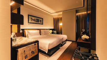 A hotel room with a large bed, a desk with a lamp, a picture on the wall, and a window with curtains.