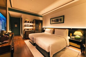 A hotel room with two beds, a desk, a wardrobe, and a nightstand with a lamp. - Hotel Central (Macau)