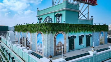 Een gebouw met een groene gevel, gebogen ramen en een muurschildering van een historisch pand.
