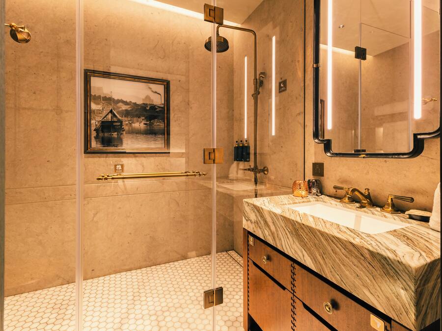 Un baño moderno con ducha de vidrio, lavamanos de mármol y un cuadro en la pared.