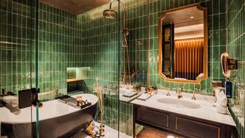 A bathroom with a large bathtub, a double sink vanity, and a mirror with a gold frame.