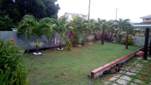 A residential garden with a lawn, palm trees, and a stone pathway. - Beausejour Buena Vista Suite 4 (Gros Islet)