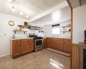 Une cuisine avec des meubles en bois, une cuisinière en acier inoxydable et un plan de travail en marbre.