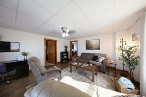 Un salon comprenant un canapé, un fauteuil, une table basse et un bureau avec un ordinateur.