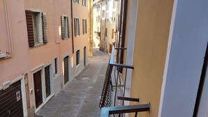 Una calle urbana estrecha con edificios a ambos lados, que incluyen balcones y una senda peatonal.