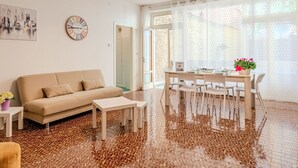 Una sala de estar moderna con un sofá beige, una mesita de centro y un comedor con mesa y sillas.