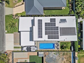 Vue aérienne d’une propriété résidentielle dotée d’une piscine, de panneaux solaires et d’un garage.