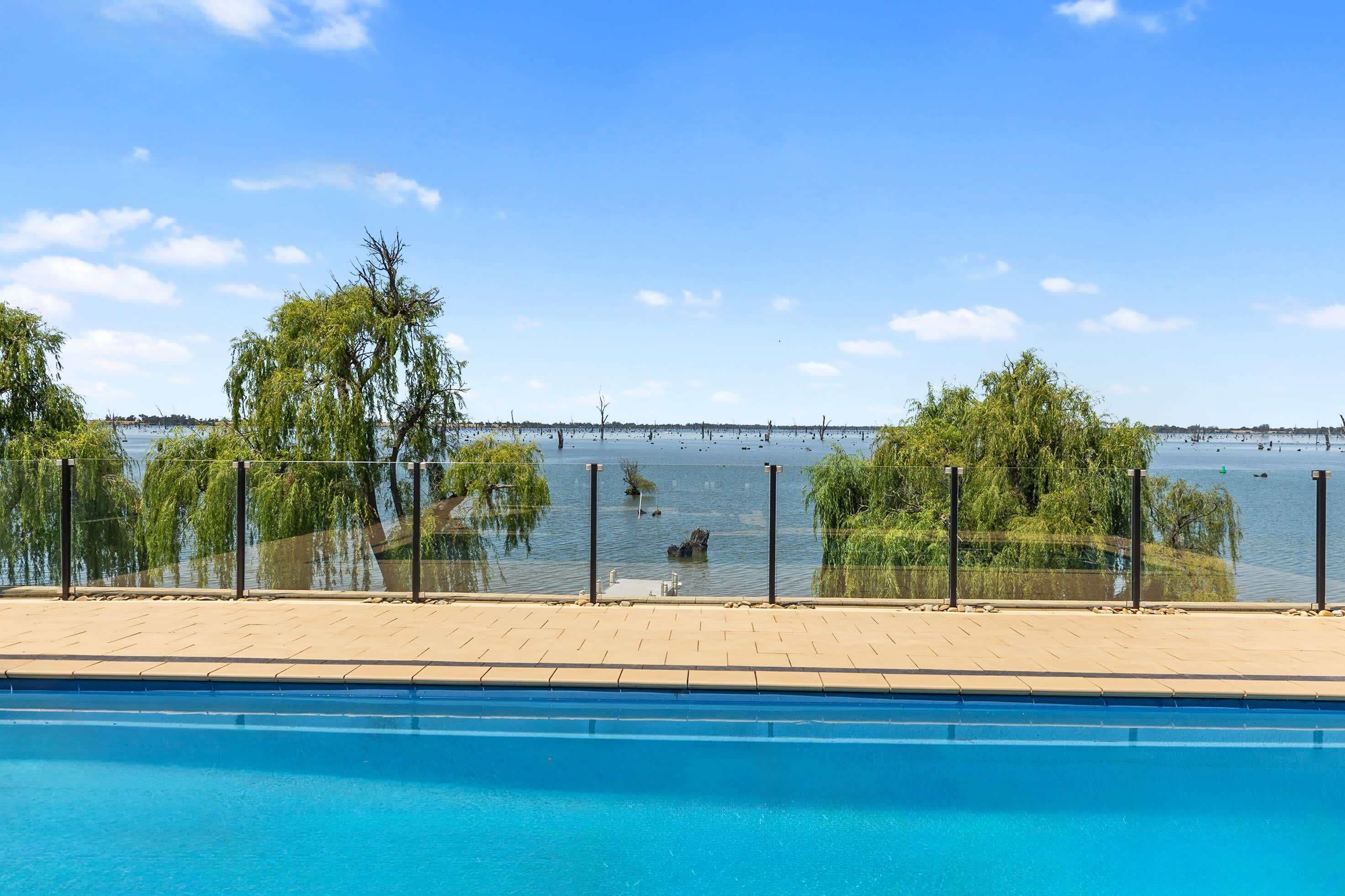 A swimming pool with a view of a lake and trees.