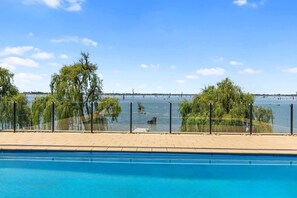 Ein Schwimmbecken mit Blick auf einen See und Bäume.
