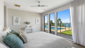 A bedroom with a large bed, a ceiling fan, a view of a pool and greenery through a sliding glass door. - The Rosemary Lakehouse - Spring Offer (Yarrawonga)
