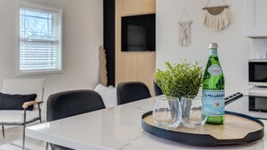 Une cuisine moderne avec un plan de travail en marbre, une bouteille verte d’eau pétillante Pellegrino et une petite plante en pot.