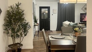 A dining area with a wooden table, chairs, and a potted plant. There is a black door with a star-shaped window and a sign that says "The guest." - Charming, cozy 3-bedroom country home in beautiful Seguin, TX (Seguin)