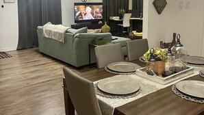 A modern living room with a sofa, TV, dining table, and chairs. - Charming, cozy 3-bedroom country home in beautiful Seguin, TX (Seguin)