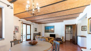 Un comedor con una mesa redonda, sillas, una lámpara de araña y una chimenea.