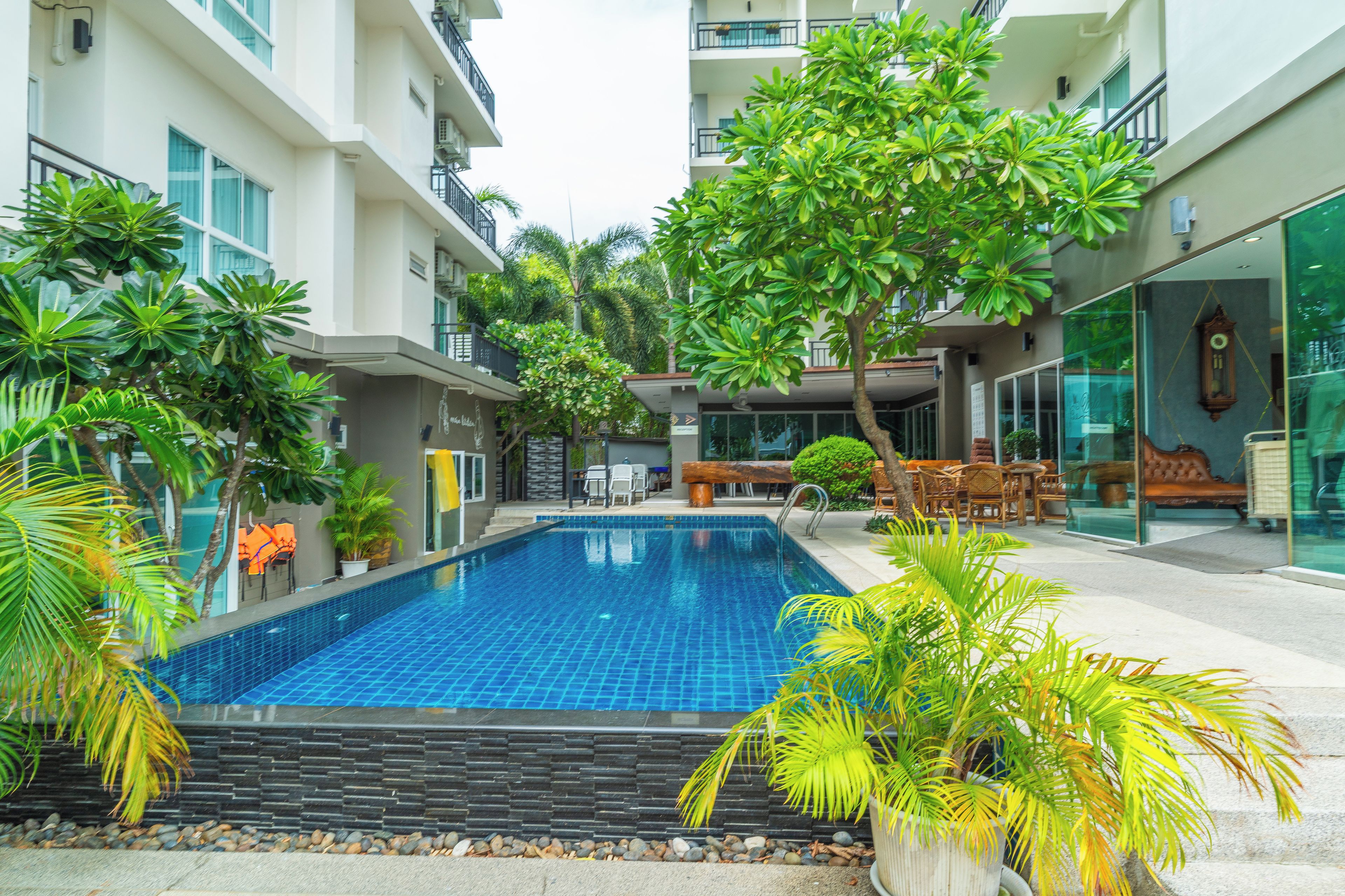 A swimming pool surrounded by lush greenery and modern buildings.