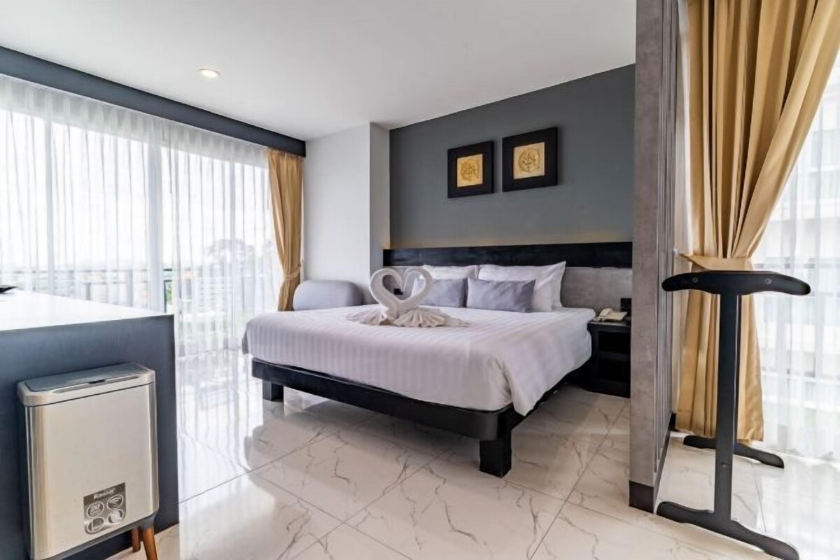A hotel room with a bed, bedside table, and a desk with a chair.