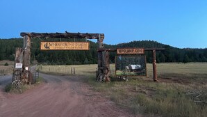 A rustic wooden archway with signs for Whispering Pines Covered Wagon Resort and WPGLAMP.COM.