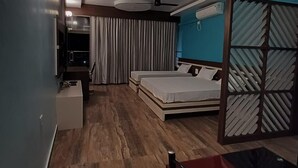 A modern hotel room with a wooden floor, a bed with a headboard, a desk, and a chair. - River King City Palace (Guwahati)